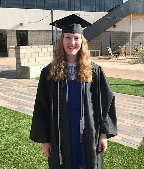 a young woman with a cochlear implant wearing her graduation cap and gown