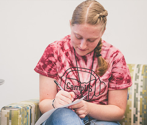 young woman with a cochlear implant does her homework on a chair