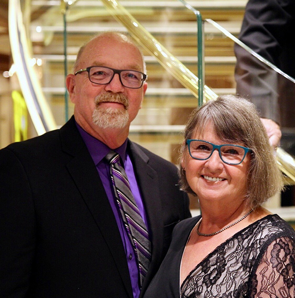a mature man with a cochlear implant stands next to his wife